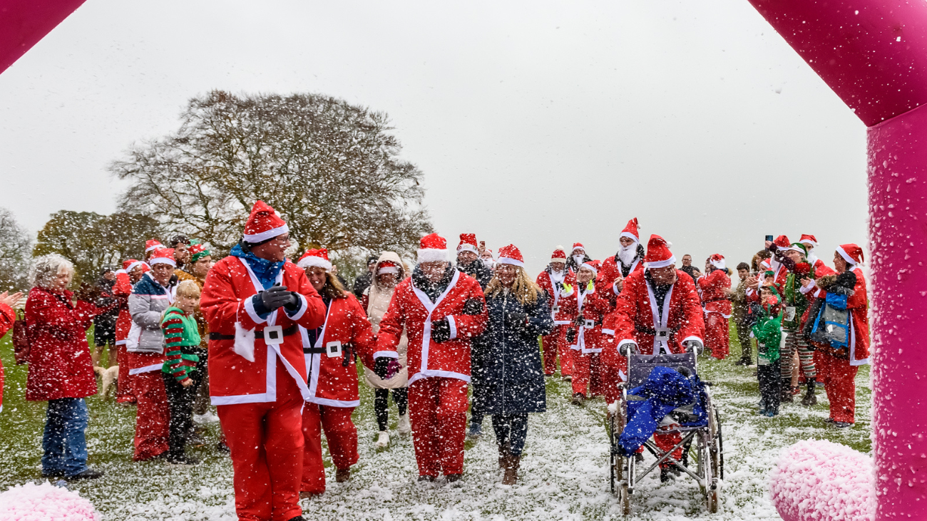 Supporters dressed as Santas crossing the finish line at Santa and Elf Run