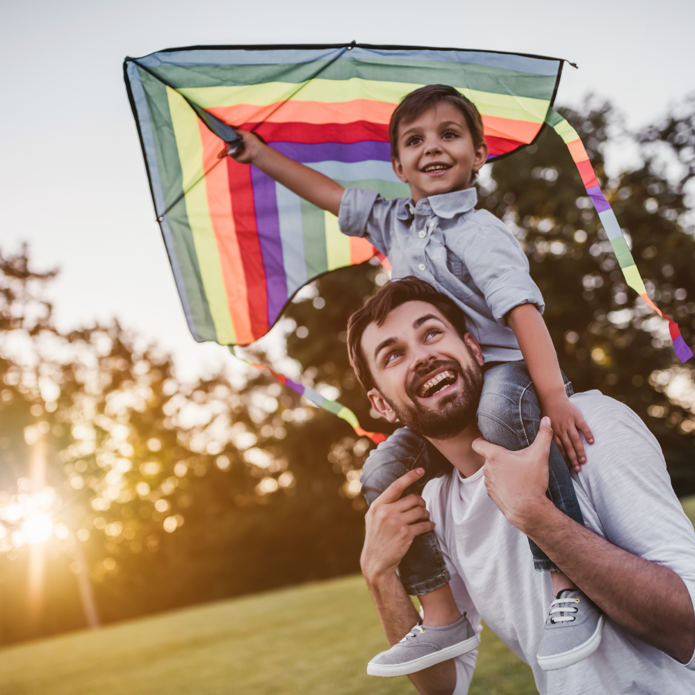 Man holding boy on his shoulder with kite