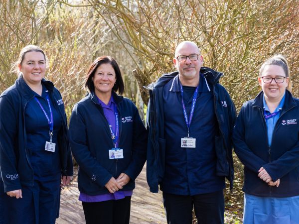 Four nurses stood outside in a garden wearing uniform