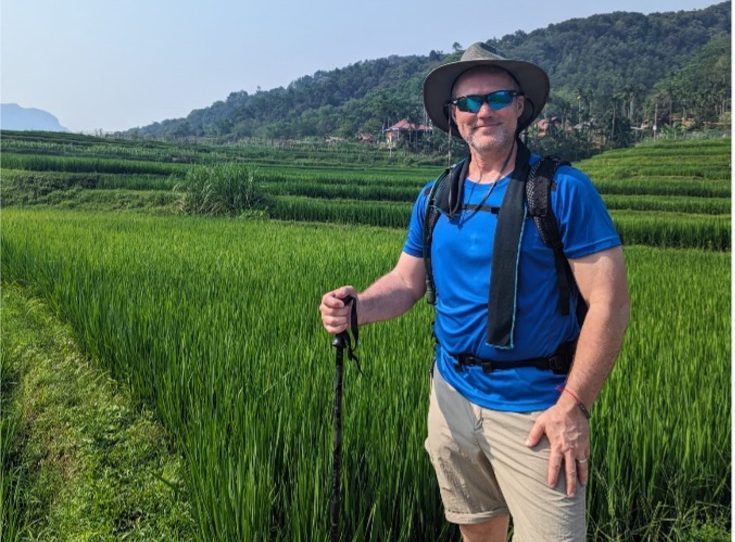 Hospice trekker holding hiking stick smiling whilst trekking through Vietnam 