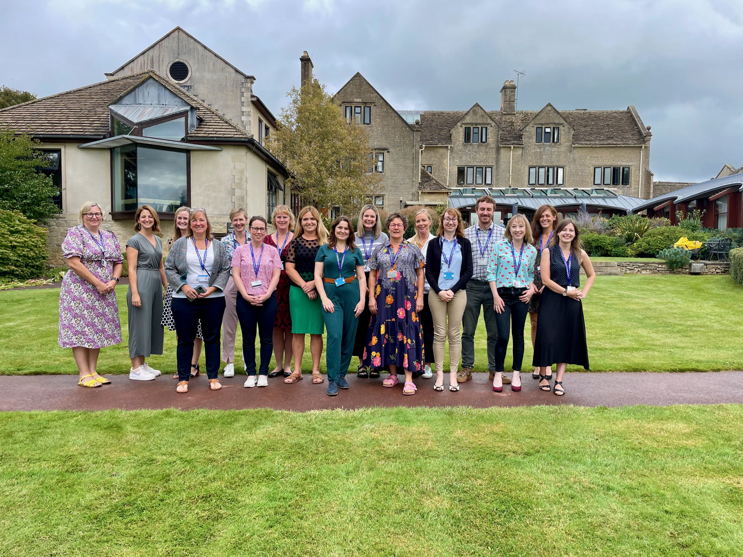 18 members of Dorothy House staff, smiling and huddled together outside of the Hospice 